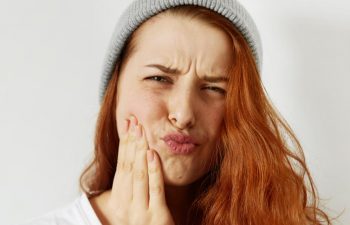 Young ginger-haired woman suffering from dental pain.