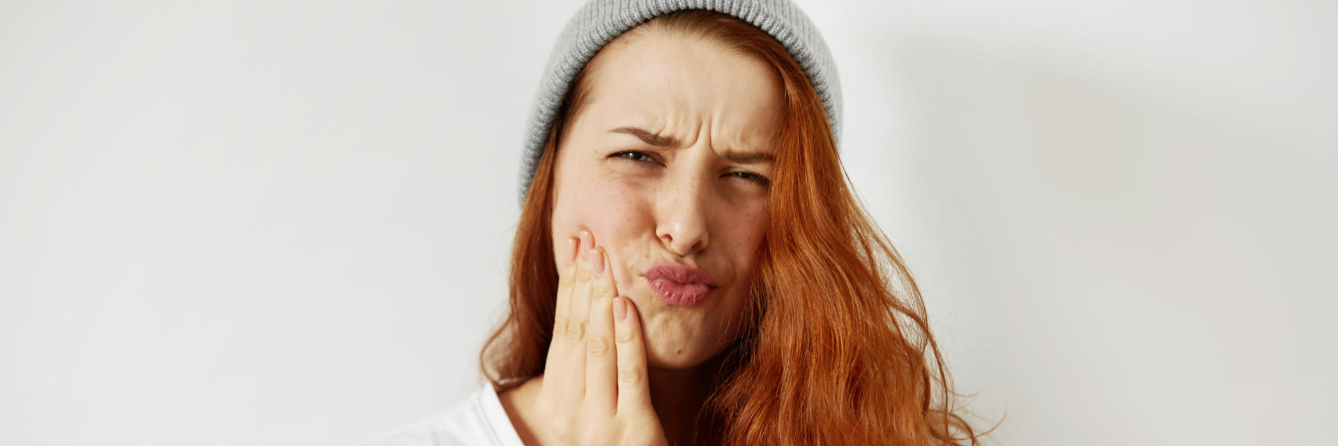 Young ginger-haired woman suffering from dental pain.