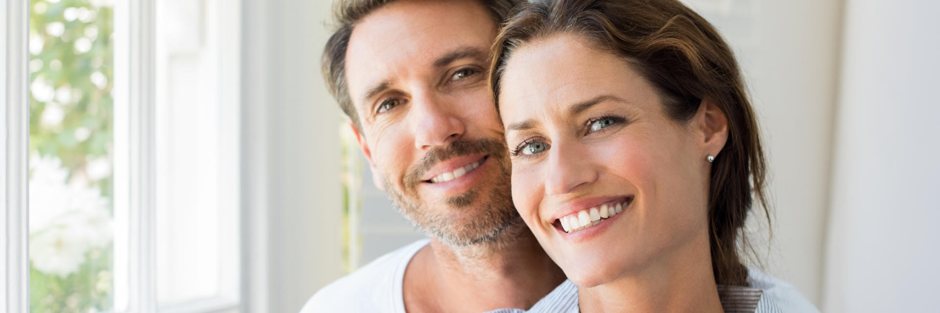 Happy middle-aged couple showing their nice teeth after dental crowns treatment in their smiles.