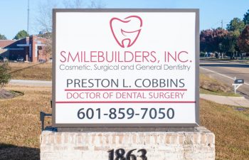 SmileBuilders, Inc. informative sign in front of the dentistry building.