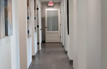 A corridor with paintings on the walls at SmileBuilders, Inc. Cosmetic, Surgical and General Dentistry.