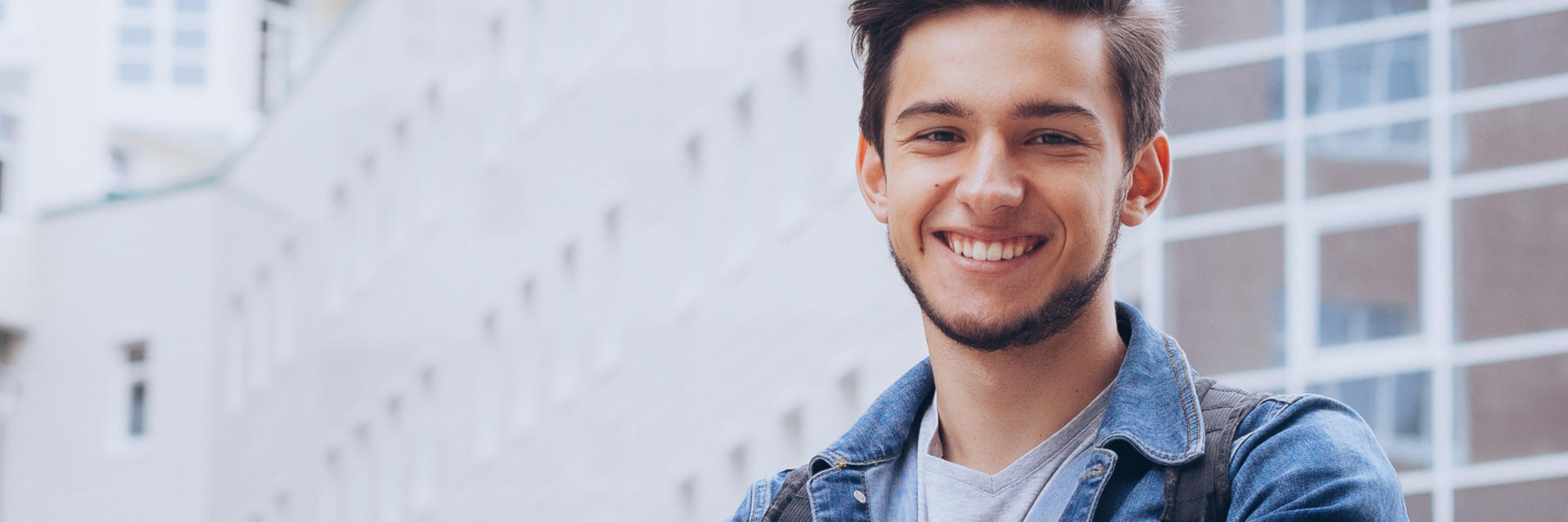 Happy young man with perfect smile in front of office buildings.