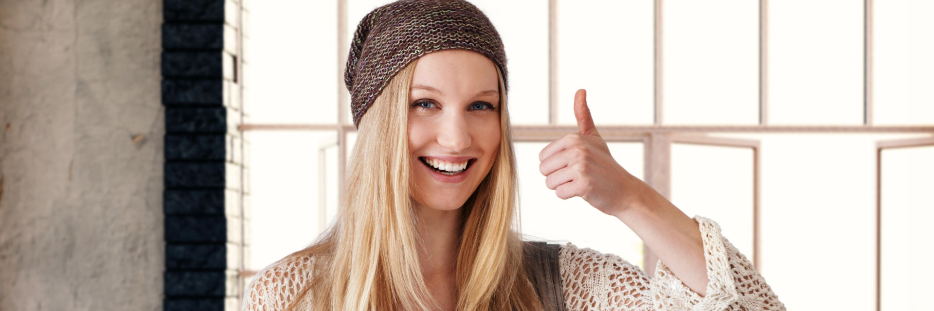 Young blonde woman with perfect smile showing her thumb up.