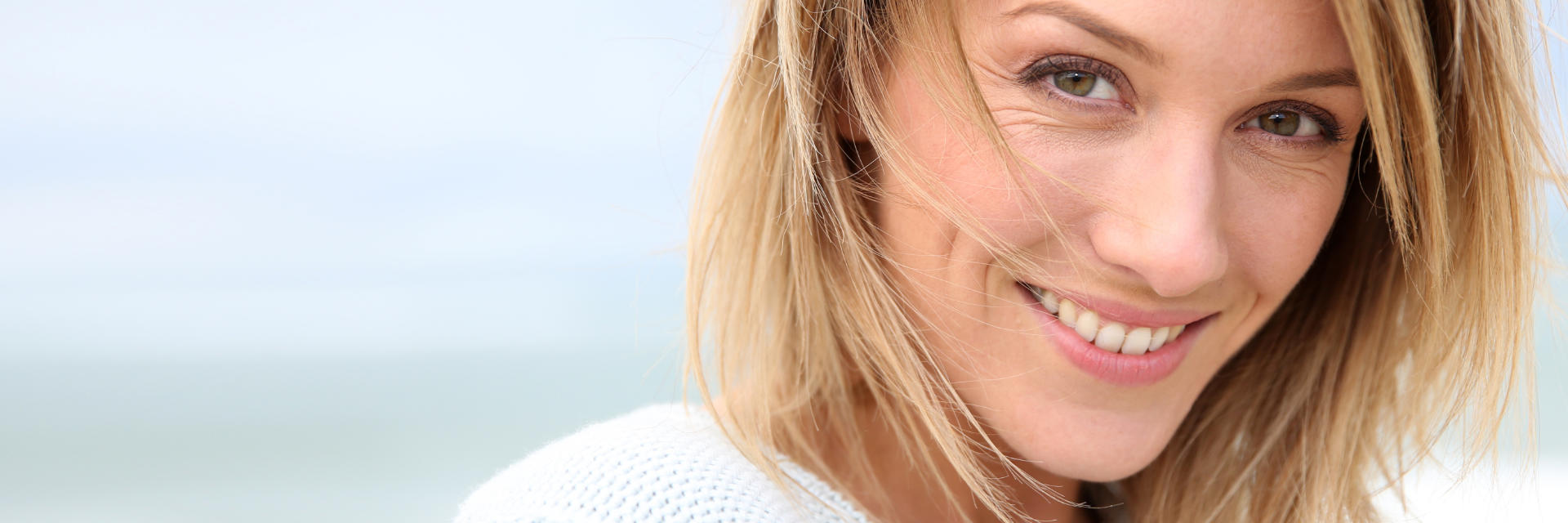 Broadly smiling blonde middle-aged woman relaxing outdoors.