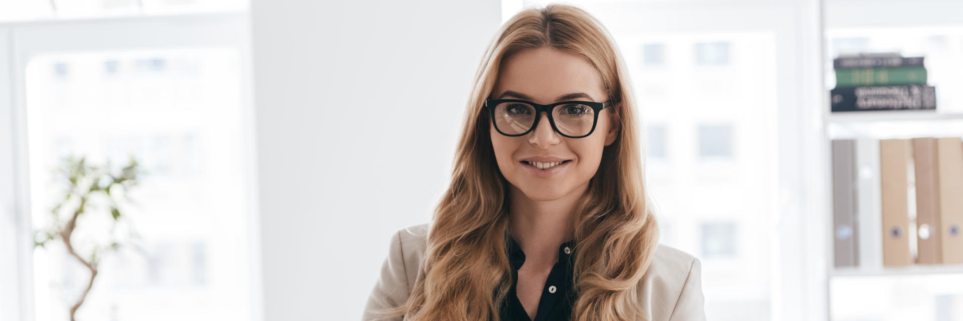 Beautiful businesswoman at her office showing beautiful healthy teeth in her smile.