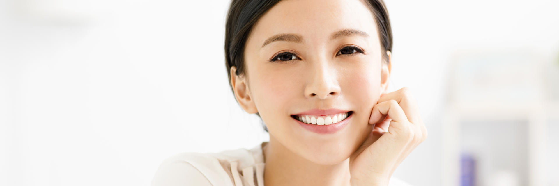 Cheerful young Asian woman showing nice whitened teeth in her teeth.