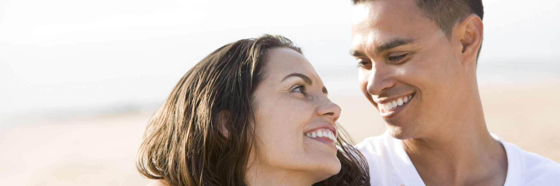 Happy couple with perfect smiles looking into each other's eyes.