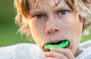 A boy inserting mouthguards before playing a match.